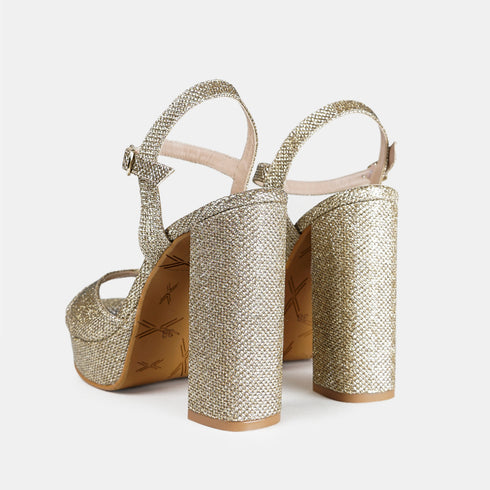 Zapatos de fiesta con tacón de doce centímetros para mujer de color dorado. Vista trasera en ángulo.